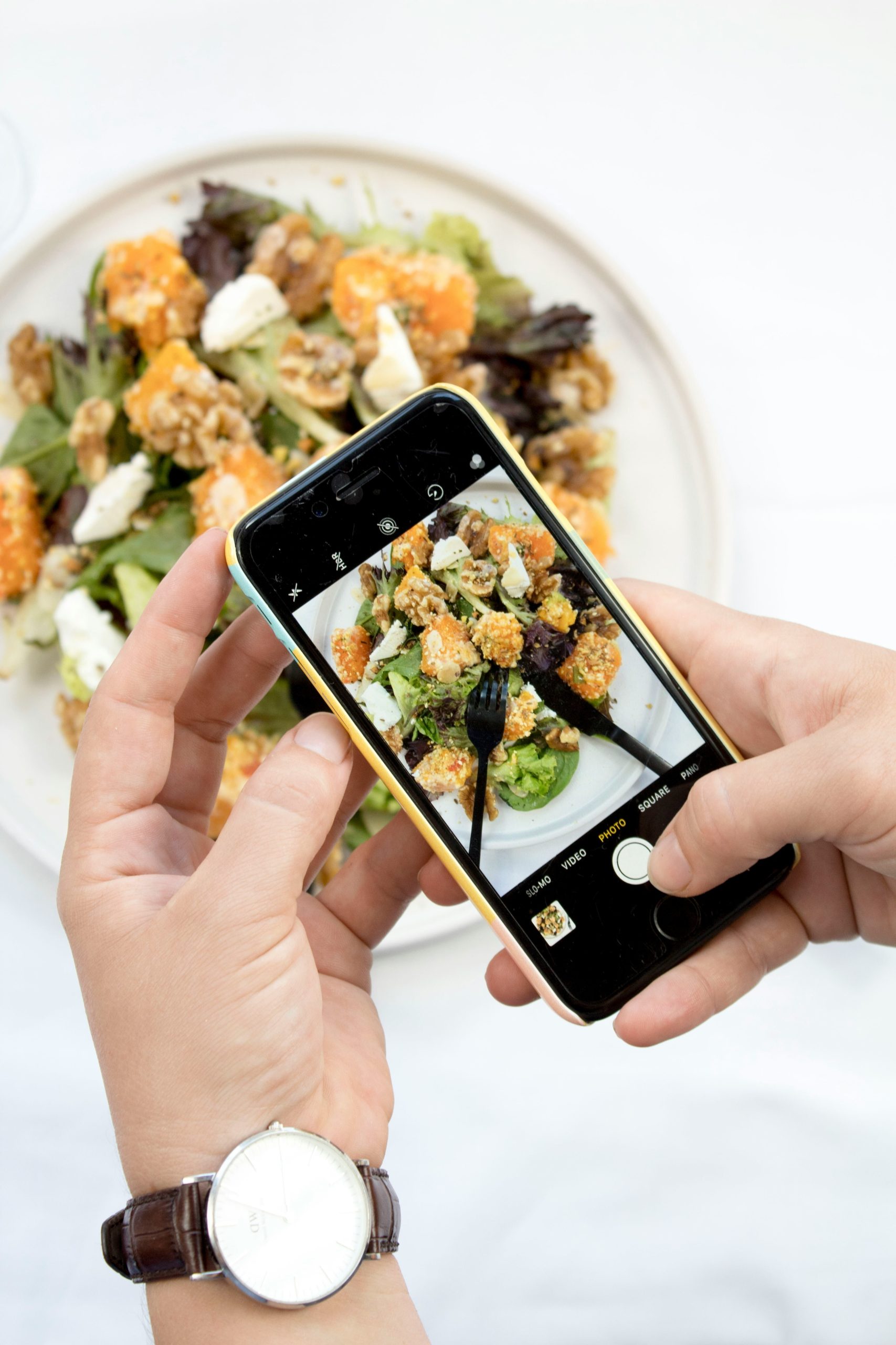 hands taking a photo of a healthy salad on an iphone - creating nutrition content ideas for dietitians